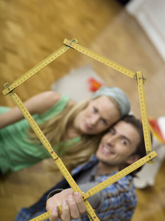 Young couple making house shape with folding rule focus on rulerの写真素材