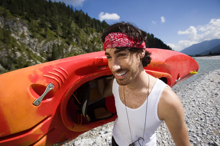 Germany, Bavaria, Tolzer Land, young man carrying a kayak smilingの写真素材