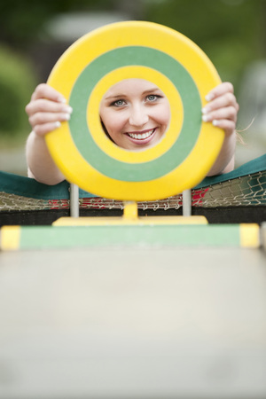 Young woman looking through plastic diskの写真素材
