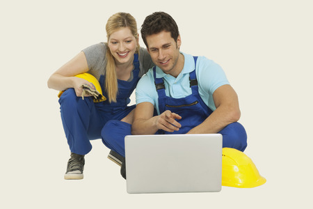 Man and woman in overall using laptop smilingの写真素材