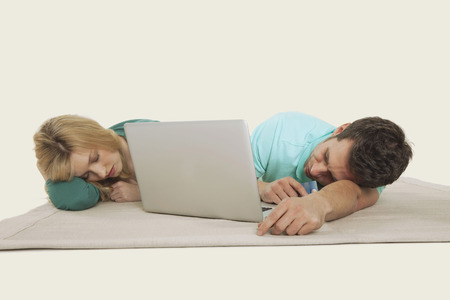 Couple lying sleeping laptop in frontの写真素材