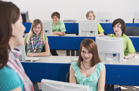 In computing class teacher explaining students smiling listeningの写真素材