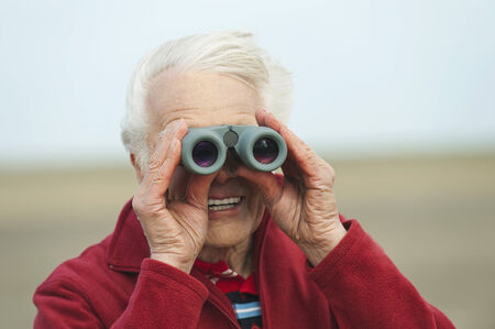 Germany, St.Peter-Ording, North Sea, Senior man looking through binocularsの写真素材