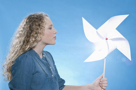 Adorable teenage girl holding paper windmill