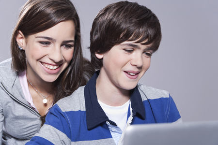 Girl and boy using laptop smilingの写真素材