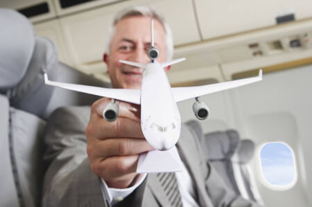 Senior businessman with model airplane on airplaneの写真素材