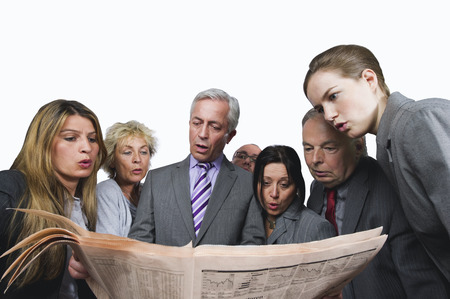 Business people reading newspaper against white backgroundの写真素材