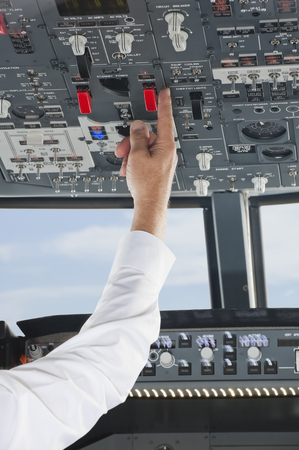 Pilot turning pushing button in airplane cockpit