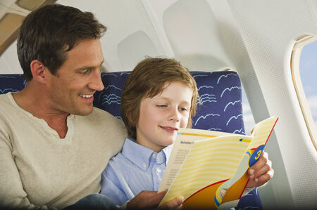 Man and boy reading book  on airplaneの写真素材