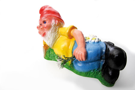 Garden gnome lying on meadowの写真素材