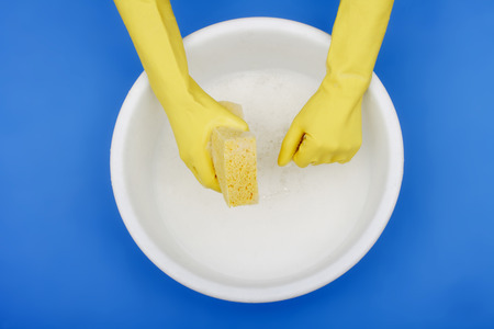 Hands wearing rubber gloves, plastic basin, spongeの写真素材