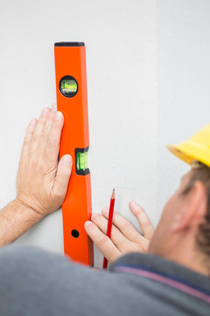 Construction worker measuring wall's straightness with spirit levelの写真素材