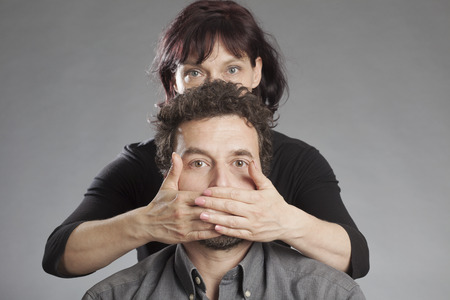 Mature couple woman covering man's mouthの写真素材