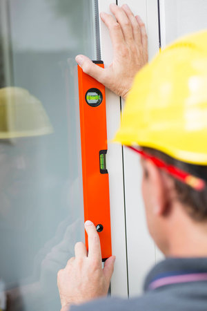 Construction worker measuring window's straightness with spirit level
