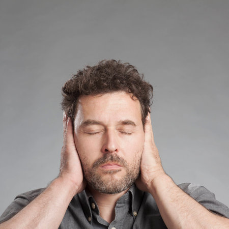 Mature man covering ears with handsの写真素材