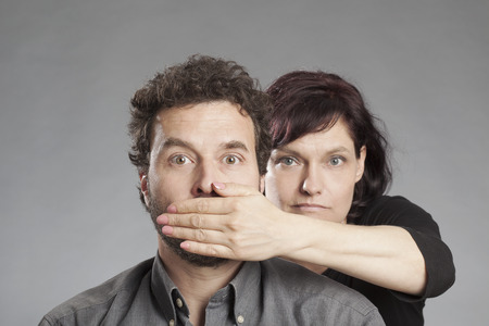 Mature couple woman covering man's mouthの写真素材
