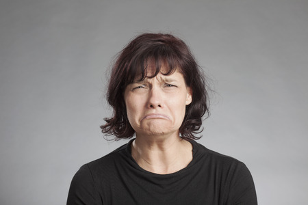 Sad brunette woman against gray backgroundの写真素材