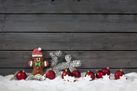 Christmas gingerbread bear christmas bulbs cinnnamon stars pine twig on pile of snow against wooden...