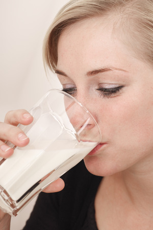 Young woman drinking glass of milk against white backgroundの写真素材