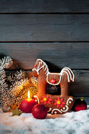 Gingerbread horse on pile of snow against wooden wallの写真素材
