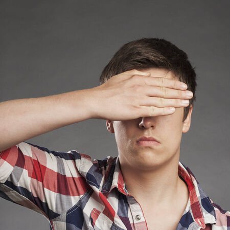 Portrait of teenager boy covering eyesの写真素材