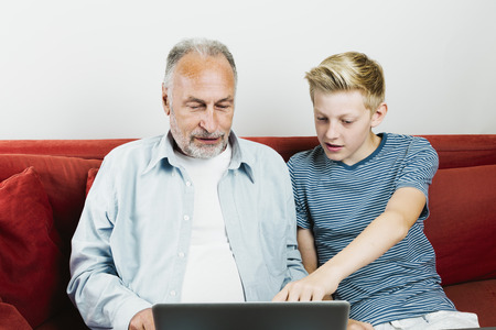 Grandson explaining grandfather how to use laptopの写真素材