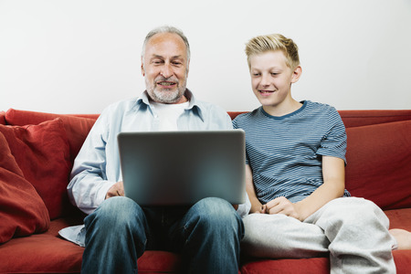 Grandson explaining grandfather how to use laptopの写真素材