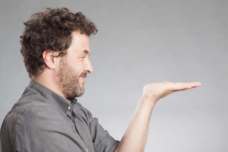 Man in grey shirt holding palm upの写真素材