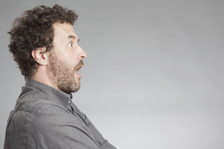 Man in grey shirt looking shockedの写真素材