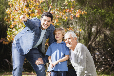 Boy in garden with grandfather and father, pointingの写真素材