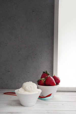 Strawberries and whipped cream in bowlの写真素材