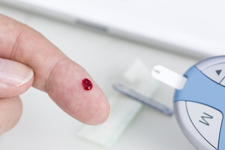 Man measuring blood sugar with glucose meterの写真素材