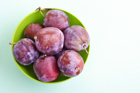 Plums, damsons in green plastic bowlの写真素材
