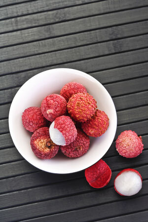 Lychees in bowl on black woodの写真素材
