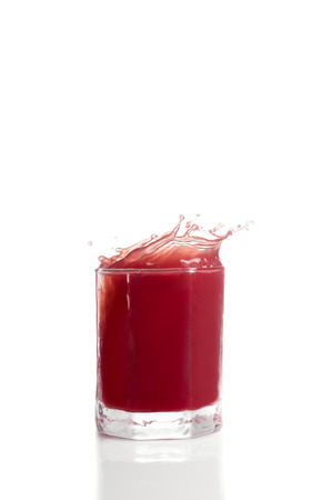 Red berry juice spilling over glassの写真素材