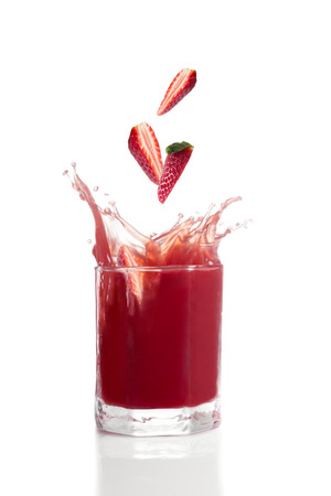 Strawberries falling into glass with red fruit juiceの写真素材