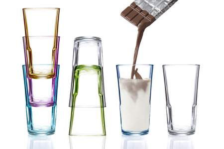 Four colorful drinking glasses, one being filled with chocolate milkの写真素材