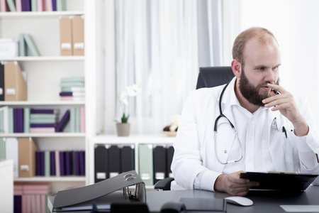 Doctor sitting at desk,reading filesの写真素材
