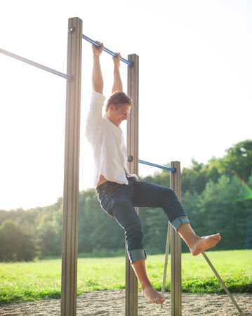 Young man exercising on bars at playground