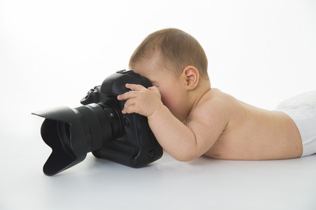 Little baby girl is playing with a big photo cameraの写真素材