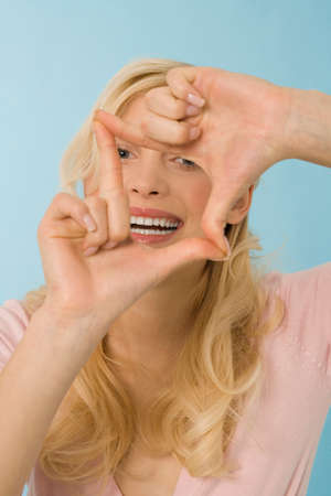 Blonde woman making hand gesture, portraitの写真素材