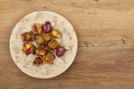 Dried roses on plate, woodの写真素材