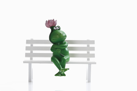 Frog figurine sitting on benchの写真素材