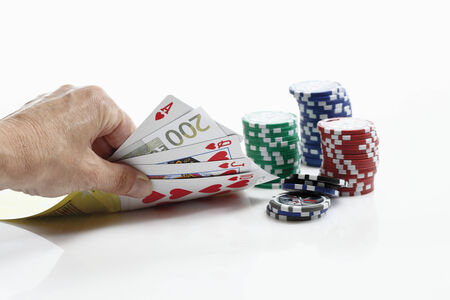 Human hand holding playing cards with gambling chips