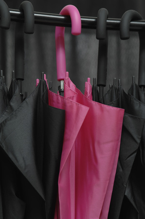 Black umbrellas with one pink umbrella, close upの写真素材