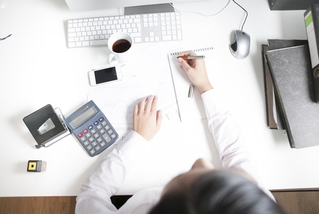 Woman working at desk, smart phone, notepad, calculatorの写真素材