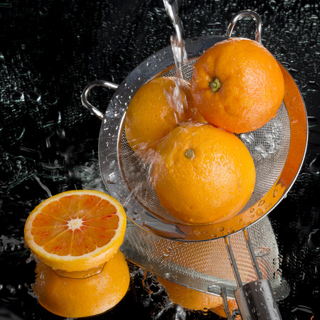 Blood oranges in colander, water