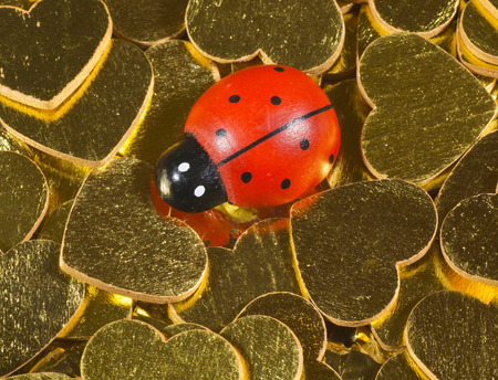 Ladybird figurine on golden heartsの写真素材