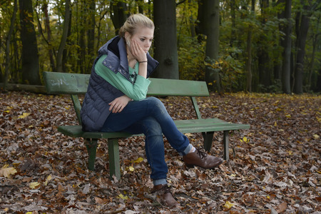 Germany, Berlin, sad young woman sitting on benchの写真素材