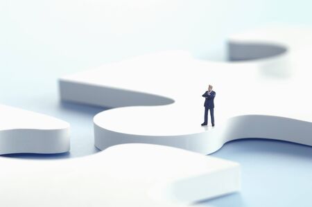 Businessman figurine standing on puzzle piece
